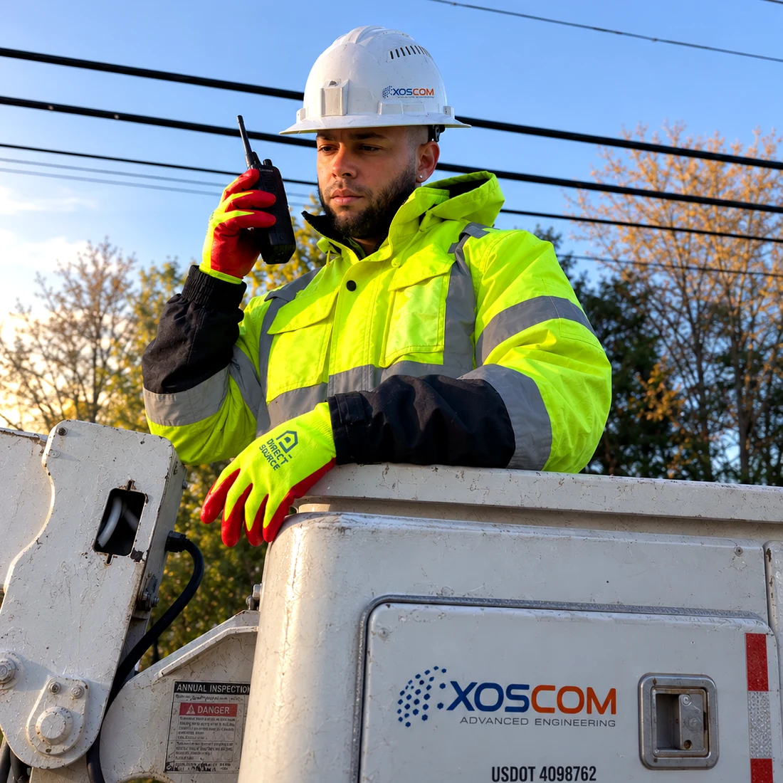 XOSCOM technician in a branded bucket truck coordinating by radio
